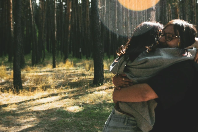 Two people hugging in a sunlit forest